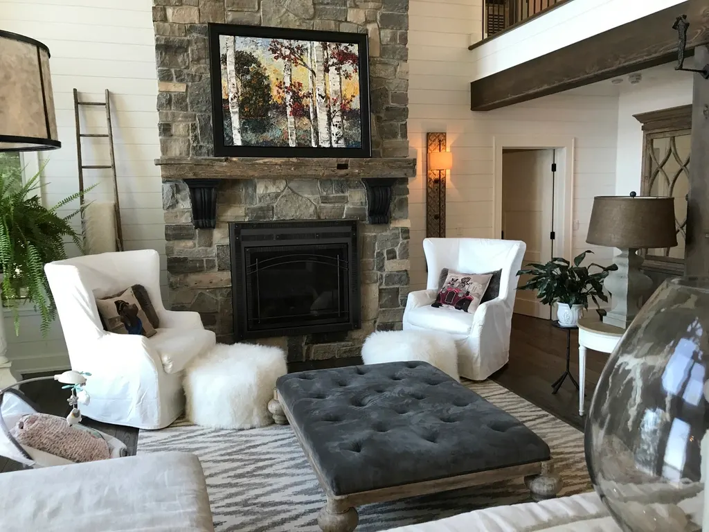 Cozy living room with a stone fireplace and white armchairs