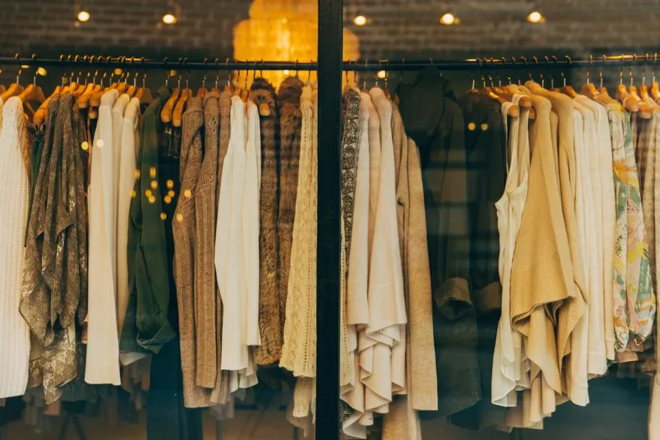 Warm-toned sweaters and jackets hanging in an open closet